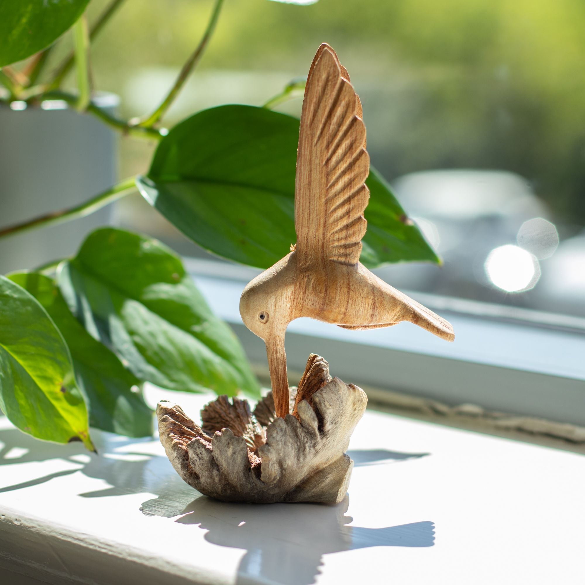 Sculpture artisanale d'un colibri buvant du nectar sur une excroissance d'arbre