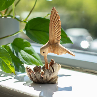 Sculpture artisanale d'un colibri buvant du nectar sur une excroissance d'arbre