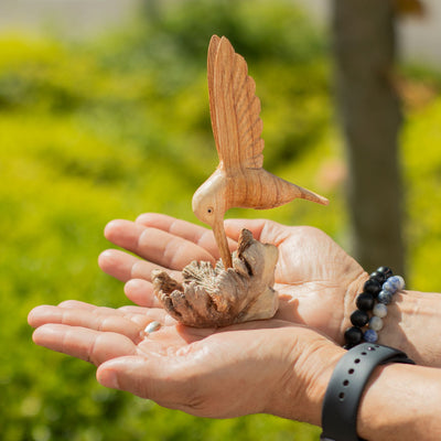 Sculpture artisanale d'un colibri buvant du nectar sur une excroissance d'arbre